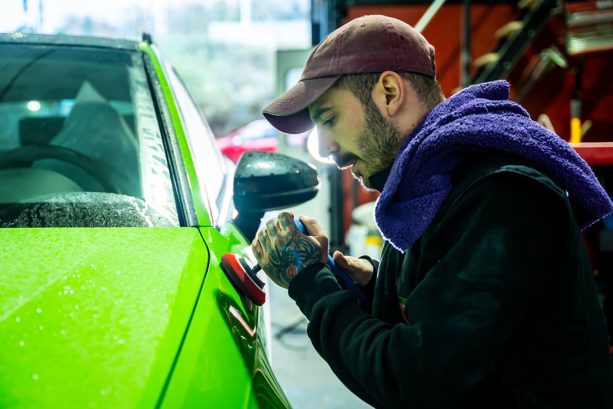 Detailer polishing the paintwork of a car to a flawless finish