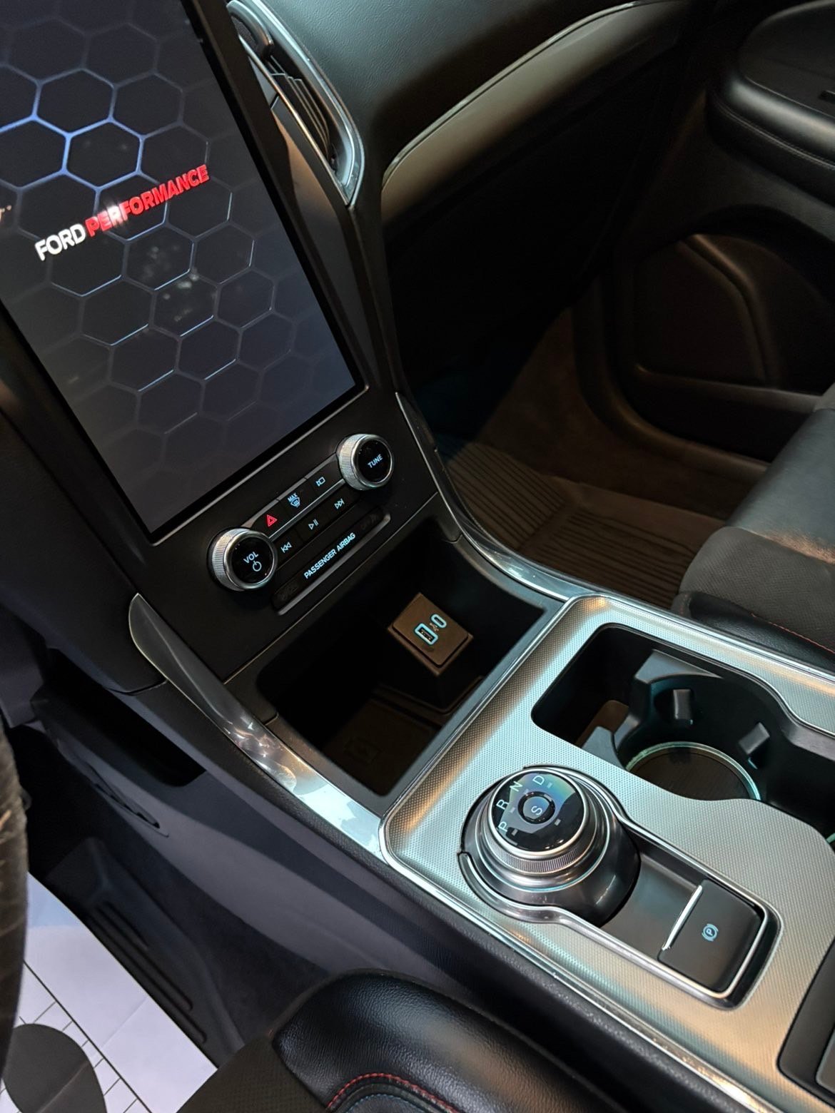 Ford vehicle interior showing digital dashboard display, climate controls, and gear shift with leather seats